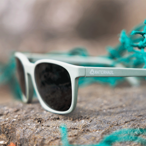 pale green sunglasses on a rocky surface with green fishing net in the background