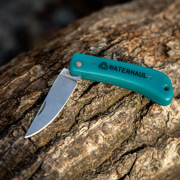 Green pocket knife resting on a wooden backdrop