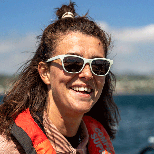 Woman wearing sunglasses with a blurred background of water and sky