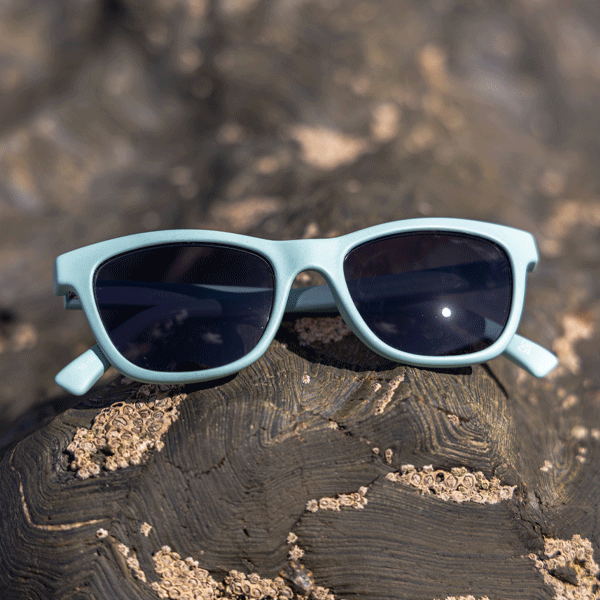 Light blue sunglasses on a textured rocky surface