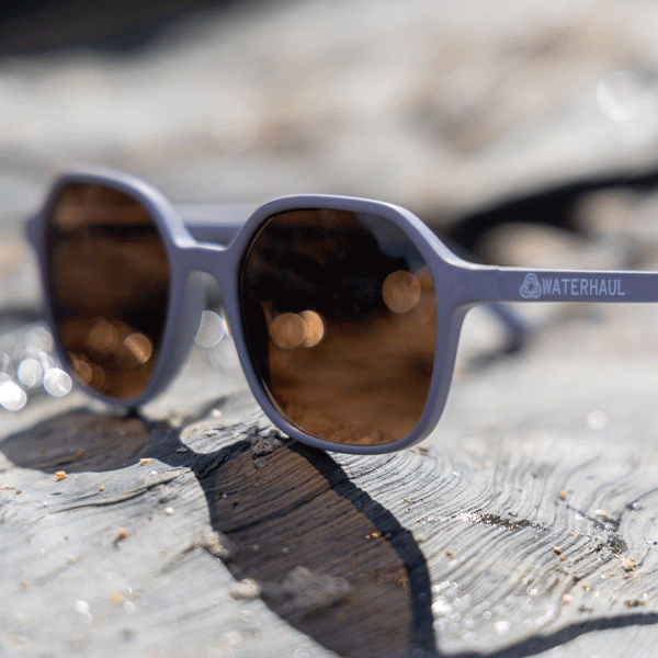Sunglasses with 'Waterhaul' brand on a rocky surface with blurred background