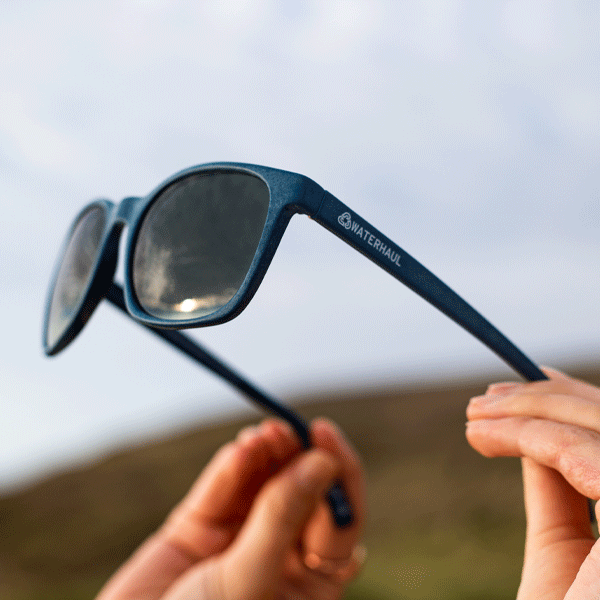 Navy sunglasses being held up to the sky