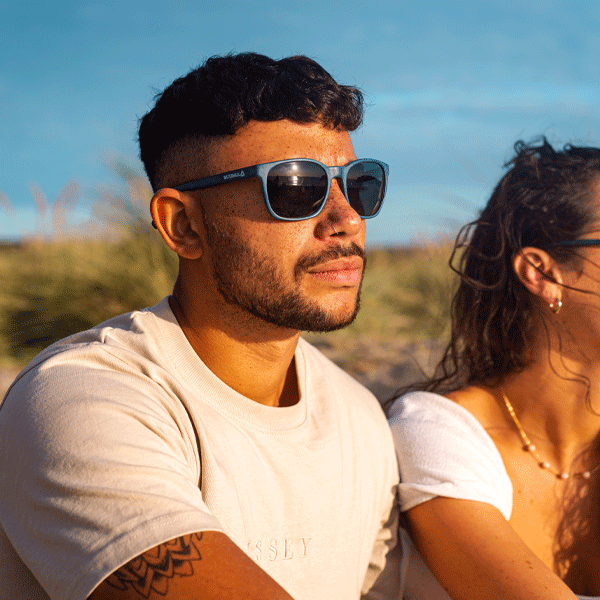 Man wearing Navy sunglasses on a beach at sunset