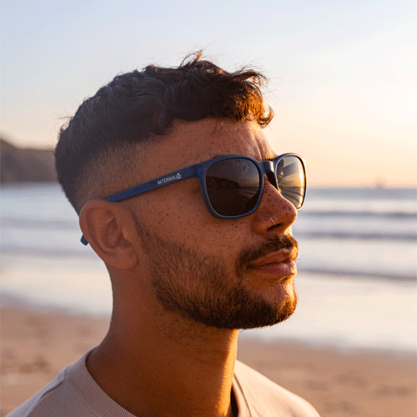 Man wearing Navy sunglasses on a beach at sunset