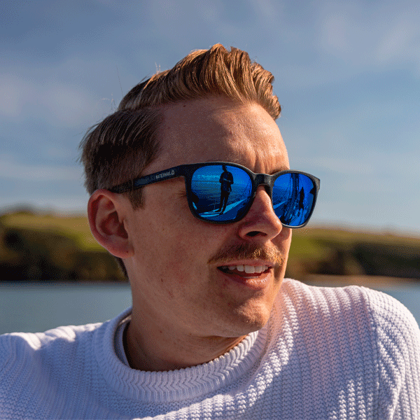 Man wearing reflective sunglasses with a scenic background