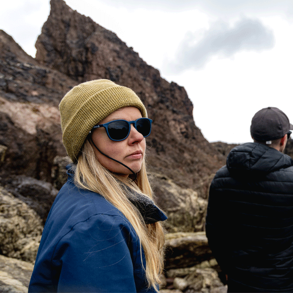 Person wearing sunglasses and a beanie in a rocky landscape