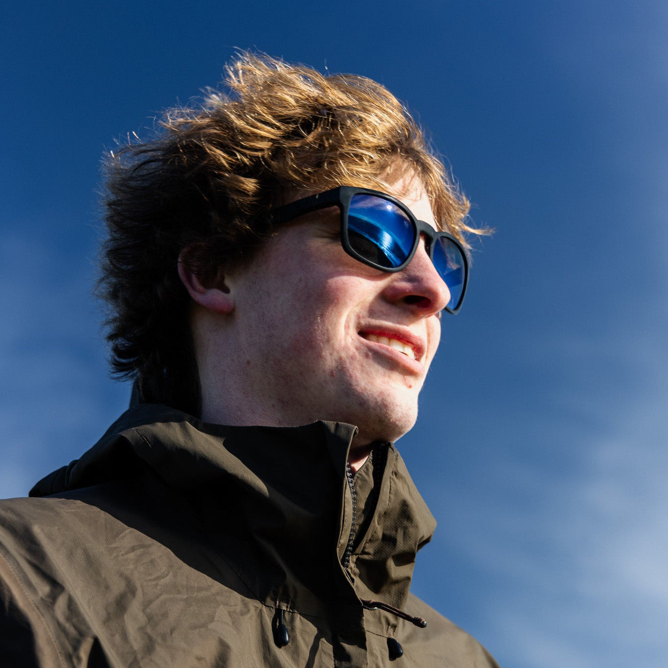 Person wearing sunglasses against a blue sky.