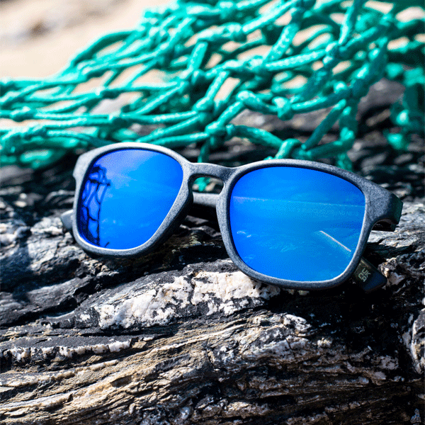 Blue sunglasses on a textured surface with green rope in the background