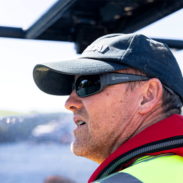 Man wearing a cap and sunglasses with a blurred outdoor background