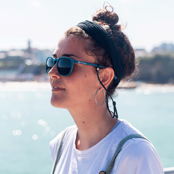 Person wearing sunglasses with a blurred background of water and sky