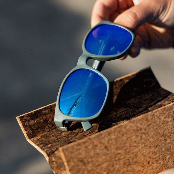 Sunglasses with blue lenses held above a cork sunglasses case